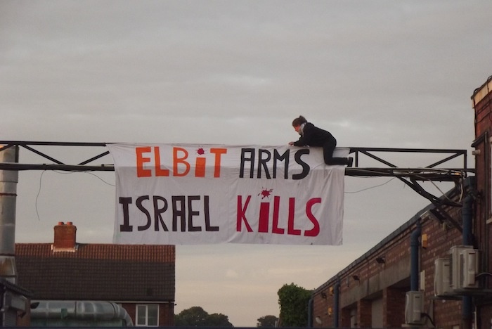 Protester-hangs-Elbit-Arms-Israel-Kills-at-shutdown-Elbit-factory-in-Birmingham-The-factory-produces-drone-engines-which-are-exported-to-Israel-and-used-over-Gaza